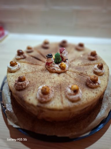 Weihnachten Kuchen mit dekorativen Sahnetuffs und kleinen Figuren, auf einem runden Teller.