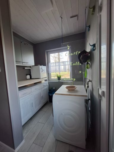Helle, moderne Waschküche mit Waschmaschine, Trockner und Fensterblick nach draußen.