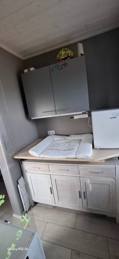 Küche mit Holzarbeitsfläche, grauen Schränken und einem Kühlschrank.