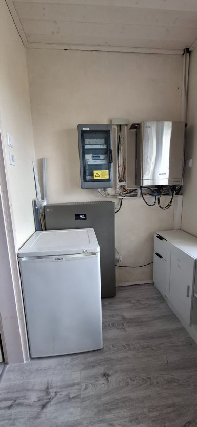 Kleine Küche mit einem Kühlschrank und einem elektrischen Zähler an der Wand.