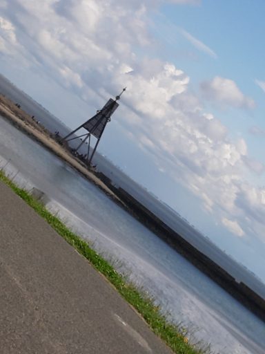 Cuxhaven Blick auf einen Hafen mit einem Wasserturm und einer Wolkenverhangenem Himmel.