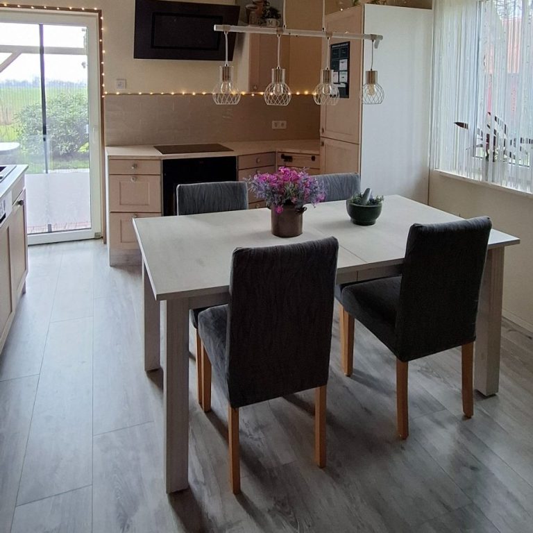 Moderne Küche mit Essbereich – Einfamilienhaus in Oederquart Moderne Küche mit einem Esstisch, Stühlen und Pflanzen auf dem Tisch. Helle Farben und Fenster.