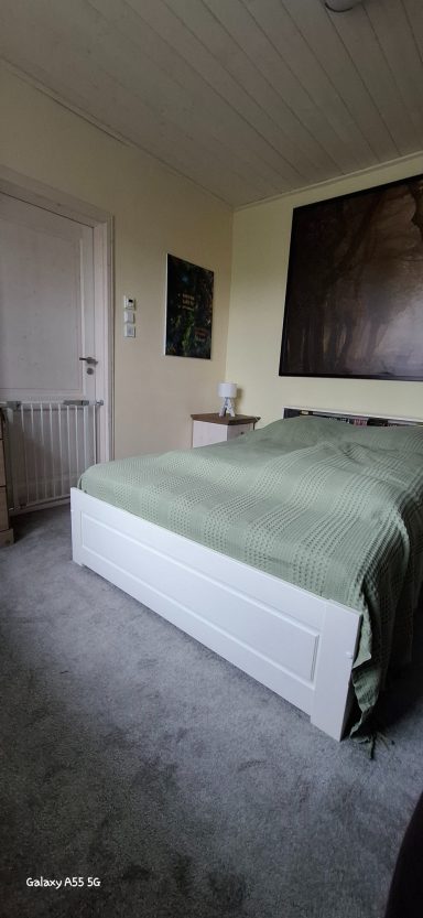 Schlafzimmer mit einem Bett, grüne Bettwäsche und einem Nachttisch.
